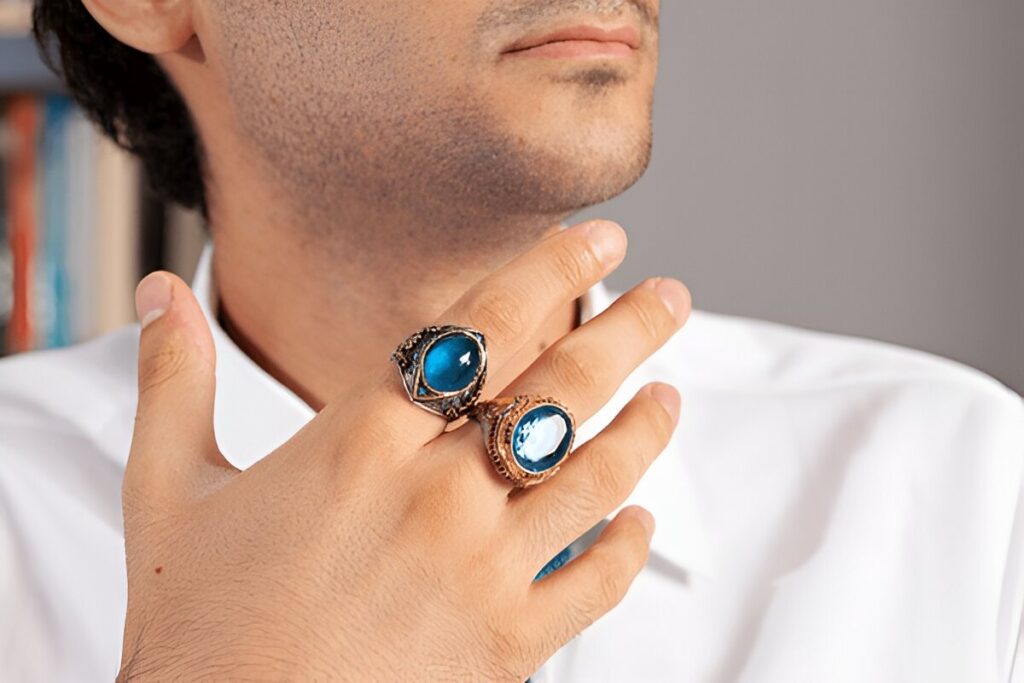 Blue silver ring on finger of man in white shirt and blue tie.