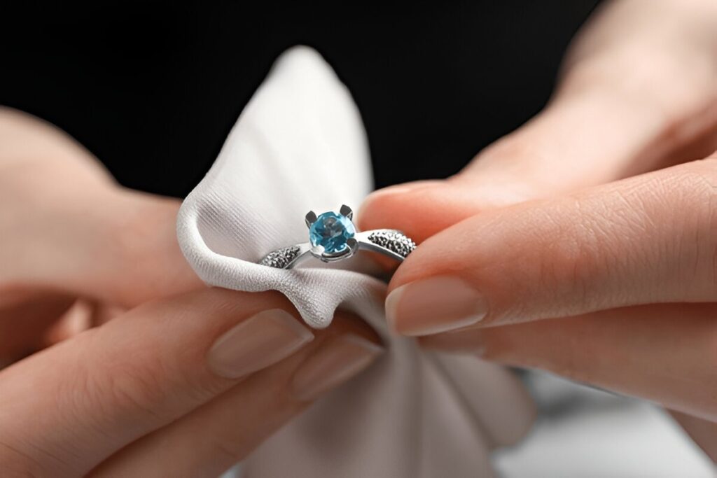 Jeweler cleaning topaz ring with microfiber cloth, closeup