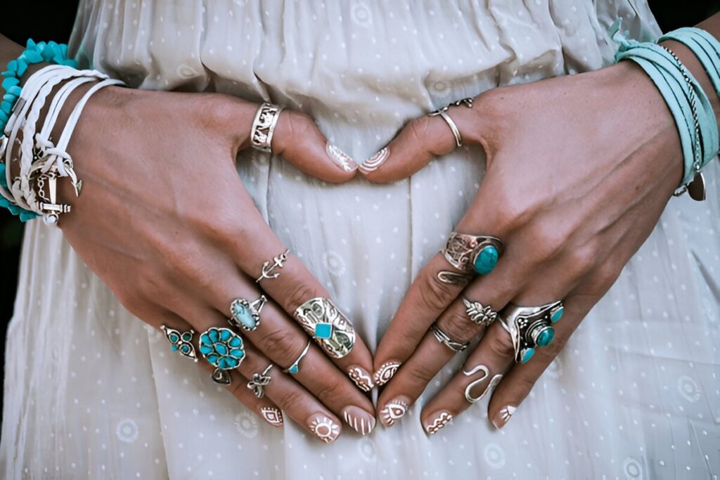 closeup of young woman hands with lot of boho style turquoise jewelry, rings and bracelets