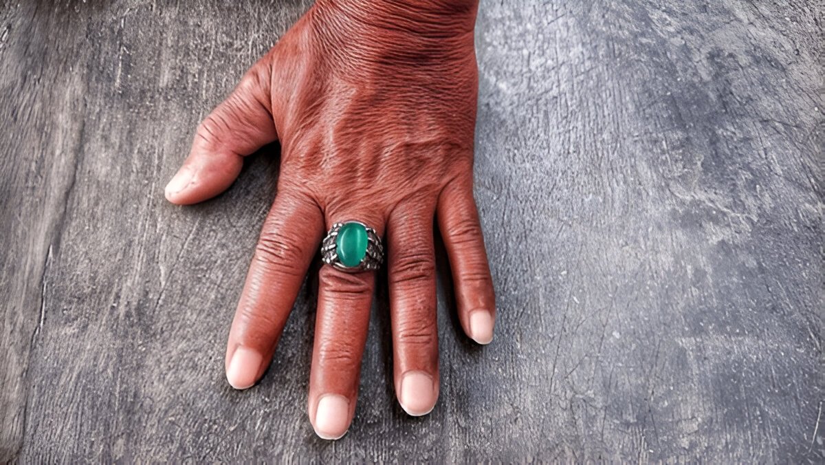 naturally textured skin wearing a ring with an emerald ring